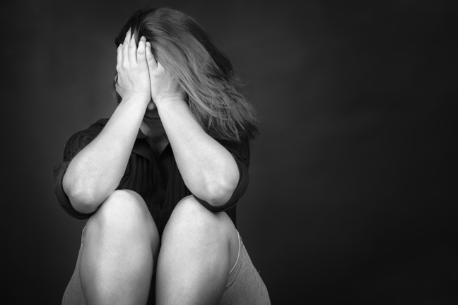 Black and white image of a very sad young woman useful to illustrate stress, depression or domestic violence