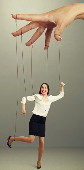 womans hand manipulating puppet over dark background